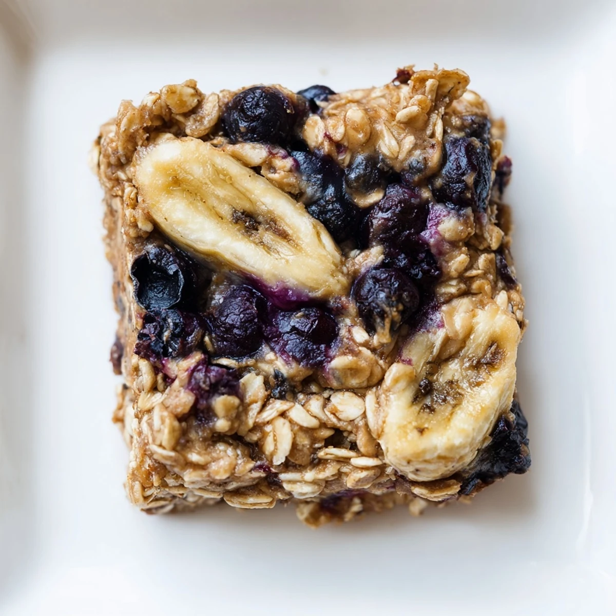 Warm, inviting photo revealing Blueberry Banana Oatmeal Protein Bars showing juicy blueberries and golden oats.