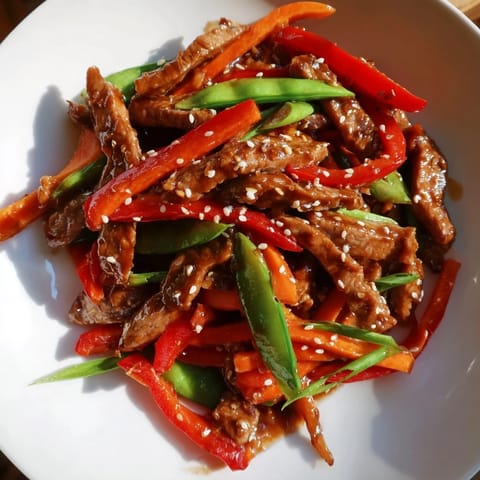 Enjoy a steaming bowl of sweet teriyaki pork stir-fry, with vibrant vegetables and savory sauce.