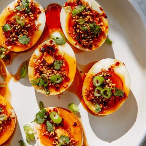 Spicy chili oil coats perfectly soft Chili Oil Eggs, garnished with fresh green onion, ready to eat.