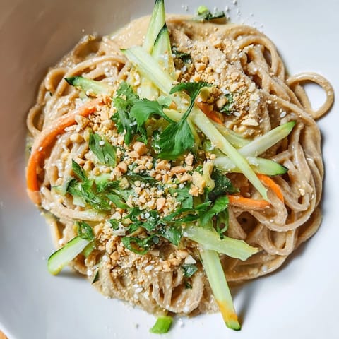 A close-up of delicious cold sesame noodles, topped with fresh cilantro and crunchy sesame seeds.