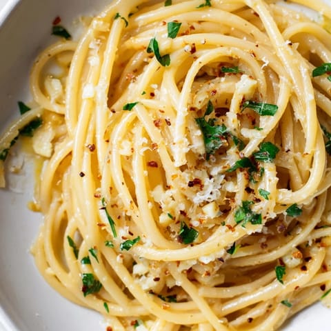 A close-up of buttery garlic linguine, enticing with fresh parsley and lemon wedges for serving.