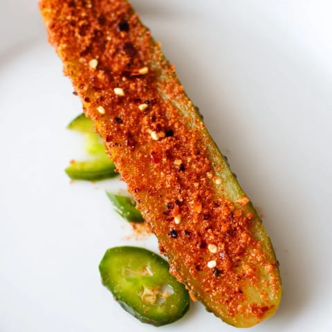 Homemade Taco Pickles served chilled in a bowl, garnished with crushed red pepper flakes and fresh cilantro for a zesty snack.
