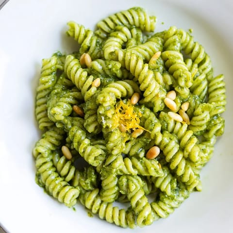 Bright Spring Green Pesto Pasta Salad served chilled with crumbled feta, lemon zest, and glistening olive oil, perfect for a fresh spring picnic.