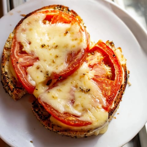 A close-up of a spicy pepper jack & tomato grilled cheese sandwich, cut diagonally to reveal a gooey interior.  