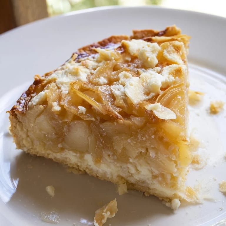 A beautiful close-up of the finished Decadent Caramelized Onion and Goat Cheese tart, garnished with herbs.