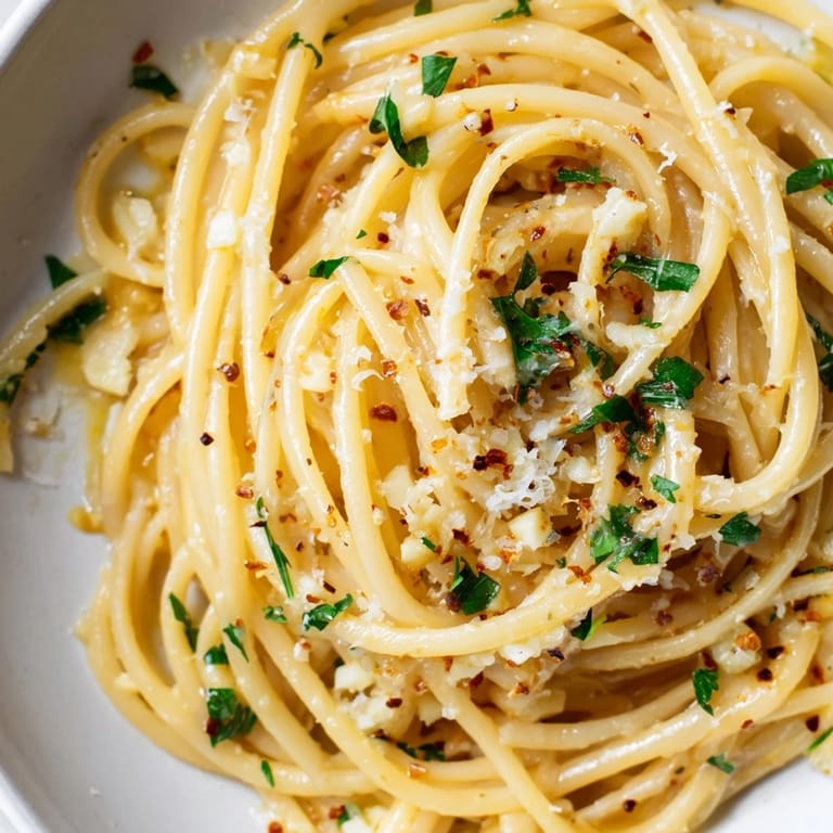 A close-up of buttery garlic linguine, enticing with fresh parsley and lemon wedges for serving.