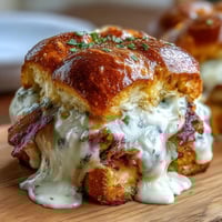 Miniature Kentucky Hot Brown sliders with turkey, bacon, and creamy Mornay sauce on soft brioche buns, garnished with fresh parsley.